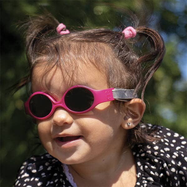 Child wearing pink sunglasses with a blurred natural background