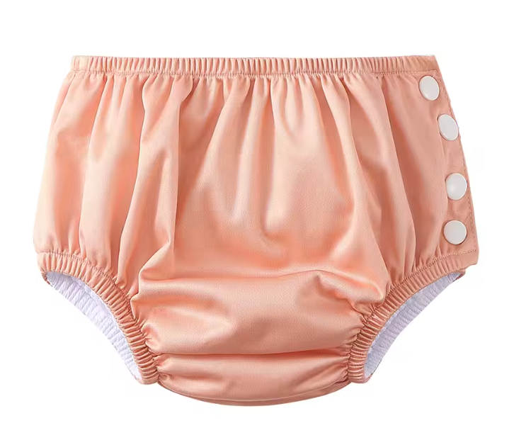 Pink baby bloomers with button details on a white background