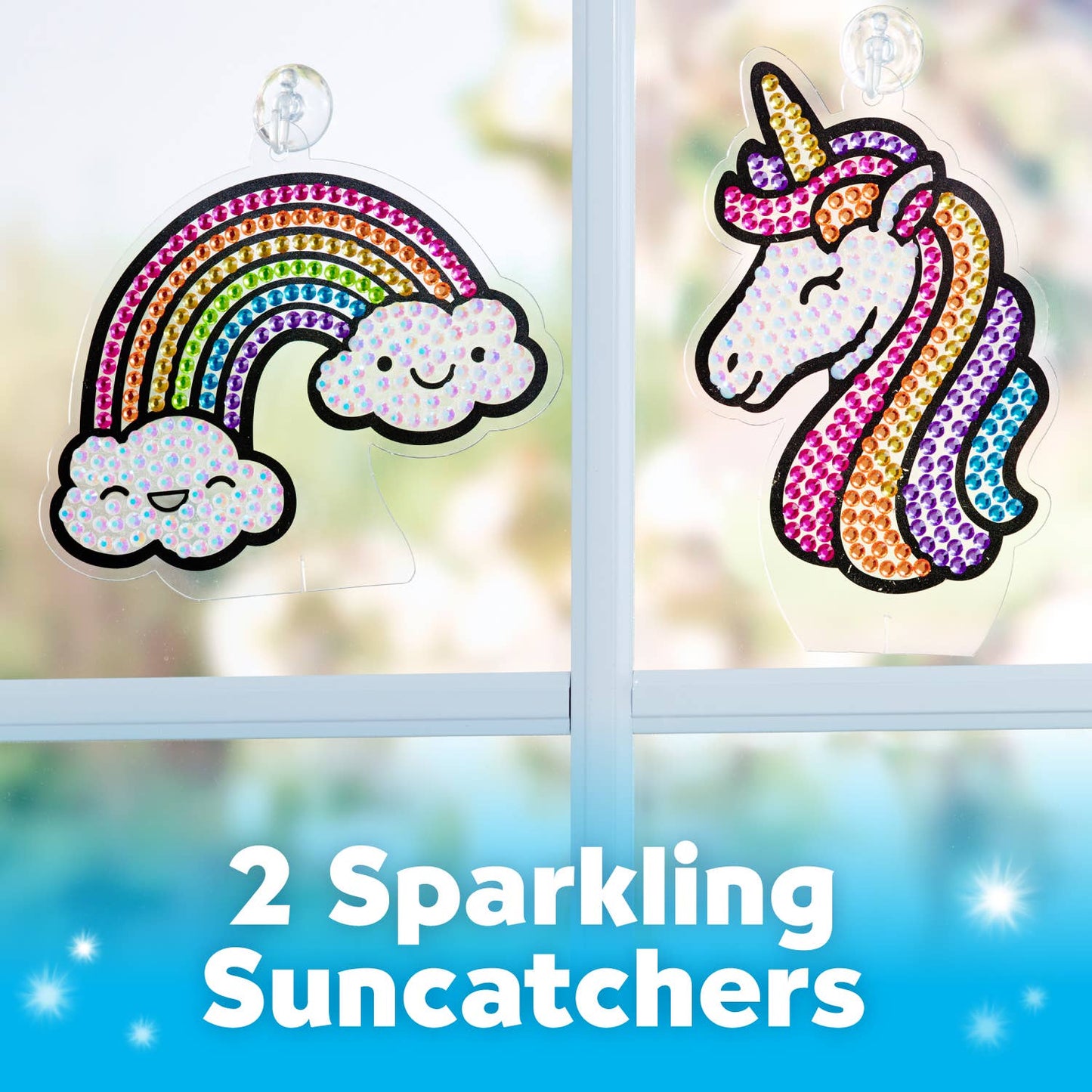 Two sparkling suncatchers, one rainbow and cloud design, the other unicorn head, on a window with a blurred outdoor background.